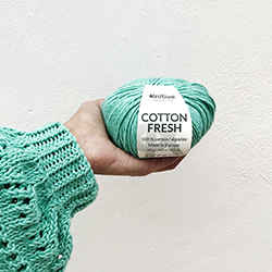 Person in a Teal Sweater Holding a Teal Ball of Yarn
